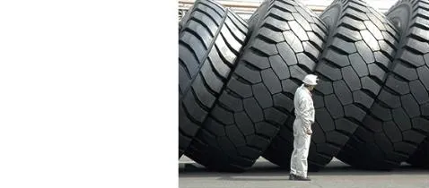 Giant Bridgestone off-the-road tyres stacked beside a technician